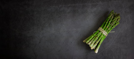 Green asparagus on a dark stone background, copy space.の写真素材