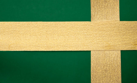 Gold ribbon on a green background. Wrapped gift texture.の写真素材