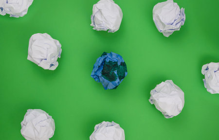 Several crumpled paper balls scattered on a green surface. Earth day concept.の写真素材