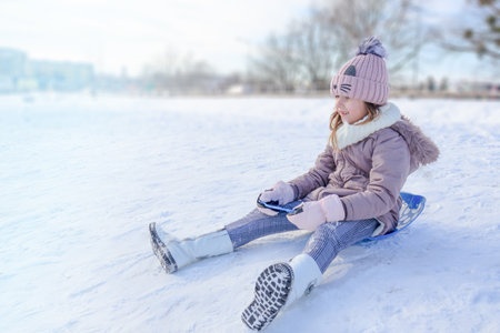 A child happily sleds down a snowy slope with joy and excitement in the winter sun.