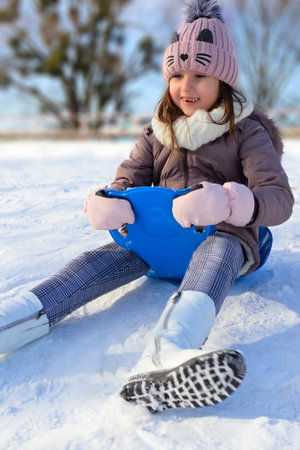 A child sleds on snow, wearing a winter coat and a cute hat, smiling with joy.の写真素材