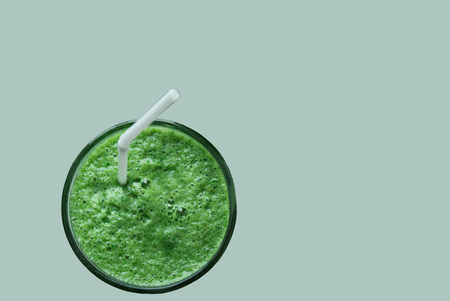 green useful for health bright smoothies in a glass with a straw on a homogeneous backgroundの写真素材