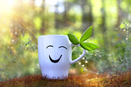 Positive cup with smile on sunny green background of nature. Greeting card. Place for your textの写真素材