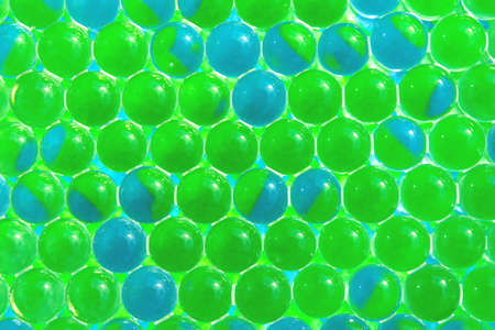 Abstract bright background. Macro of fresh color light green and blue gel balls. Imitation of globeの写真素材