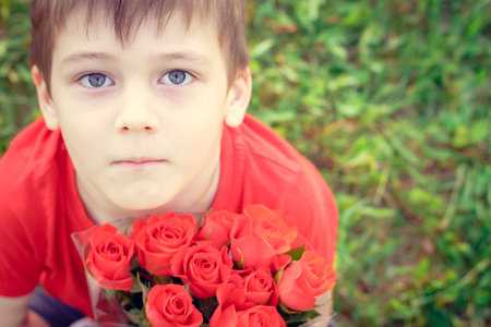 Boy with flowers. Cute baby in bright red t-shirt with roses. Portrait of child