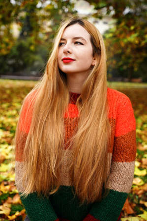 Joyful girl throws leaves in autumn park. Woman feel good outdoors in fall. Happy smiling person in nature backgroundの写真素材
