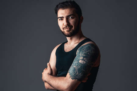 Profile of handsome guy with tattoo in studio. Caucasian strong man on black backgroundの写真素材