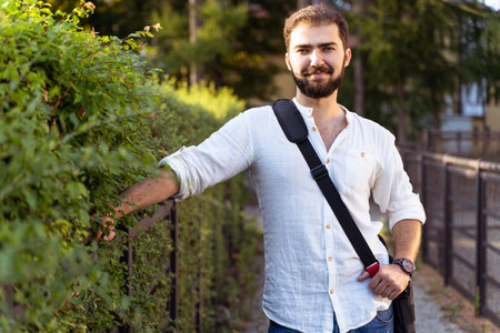 Stylish guy near brick wall drinks coffee. Hipster man with beard on city streetの写真素材