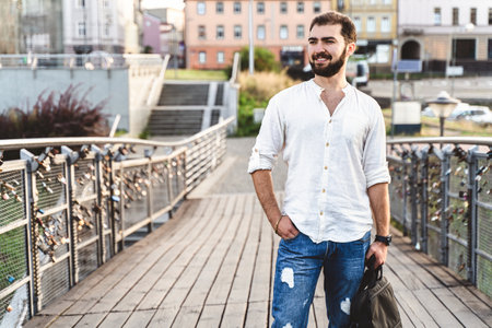 Stylish guy near brick wall drinks coffee. Hipster man with beard on city streetの写真素材