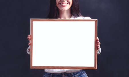 Smiling woman holding blank billboard. Girl in white shirt with poster frameの写真素材