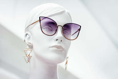 Mannequin face. Bright portrait of female beautiful dummy in purple sunglasses with earrings on isolated white background. Fashion industryのeditorial素材