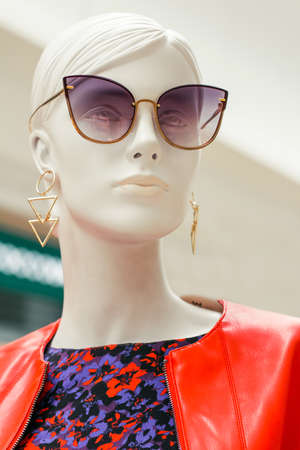 Mannequin face. Bright portrait of female beautiful dummy in purple sunglasses with earrings. Fashion industryのeditorial素材
