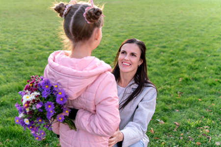 Mom and daughter hold hands outdoors. Happy girl goes to school. Everyday lifeの写真素材