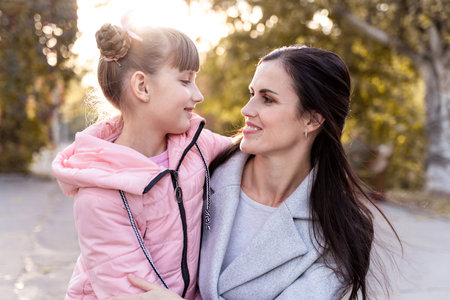 Mom and daughter hold hands outdoors. Happy girl goes to school. Everyday lifeの写真素材