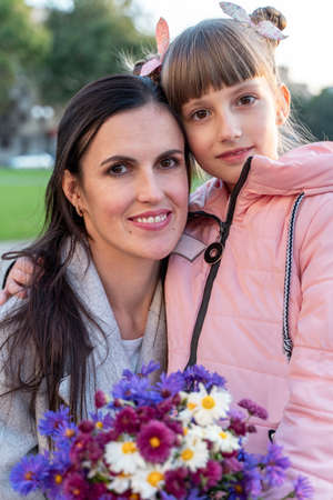 Mom and daughter hold hands outdoors. Happy girl goes to school. Everyday lifeの写真素材