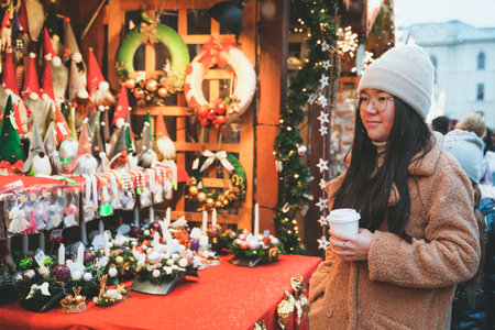 POLAND, BYDGOSZCZ - December 5, 2021: Girl looks Christmas fair. A woman walks in the new year city. Purchaser chooses giftsのeditorial素材