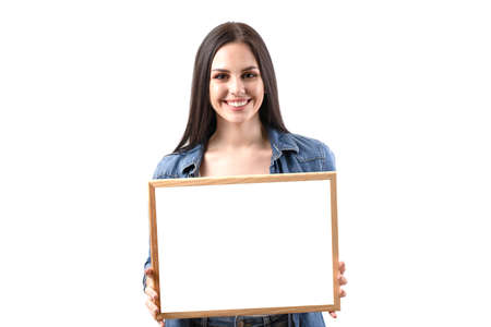 Happy smiling woman holding a poster on a white background in the studio. A beautiful girl shows an advertisementの写真素材