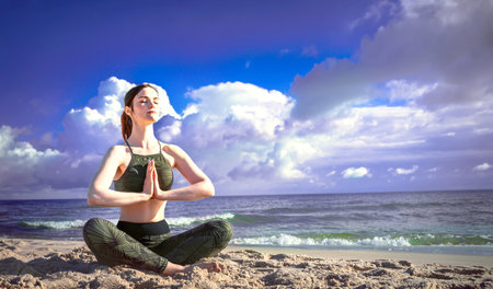 Woman in lotus position on the beach. Girl enjoys meditation outdoors. Yoga harmony of soul and body healingの写真素材