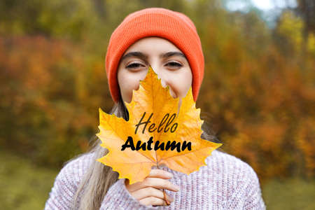 Happy girl with yellow maple leaf. Smiling young woman in autumn park. Portraitの写真素材