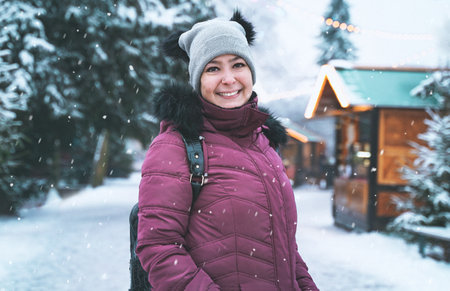Brazilian woman with beautiful smile on background of a snowy winter. Positive pretty girl in outerwear outdoors. portrait of an ordinary personの写真素材