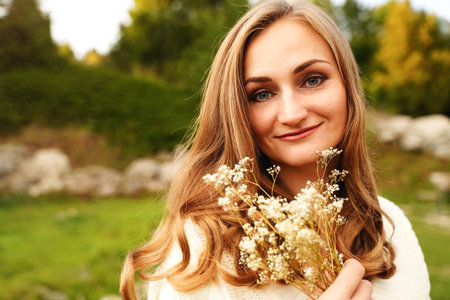 Pretty woman with blue eyes outdoors. Smiling blonde girl on the background of nature. Portrait of an ordinary womanの写真素材