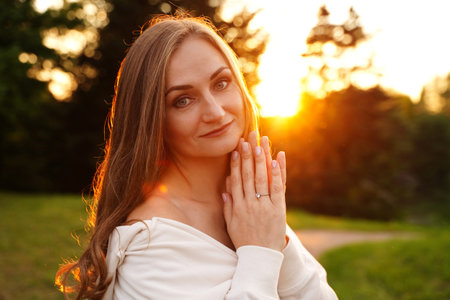 Pretty woman with blue eyes outdoors. Smiling blonde girl on the background of nature. Portrait of an ordinary womanの写真素材