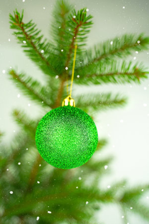 Spruce tree and shiny bauble. Bright green branch and ball on snowy background. Merry Christmas and Happy New Year. Monochrome vertical greeting cardの写真素材