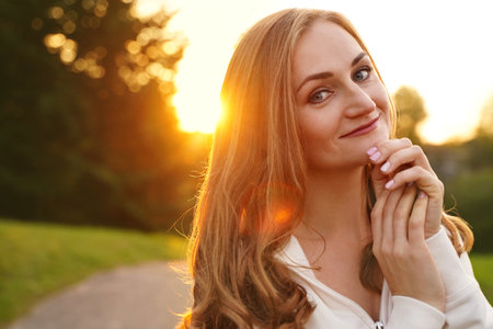 Cute blonde girl on background of sun. Ordinary happy woman enjoying life in summer. confidential personの写真素材