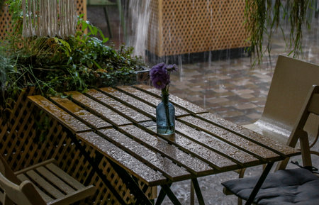 Table with water drops and chairs in a summer cafe in the rainの写真素材