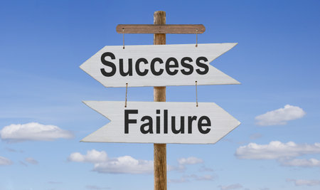 White wooden arrows with the inscription: failure - success are suspended on a rope on a wooden...