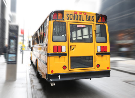 School bus driving on city street. Rear view
