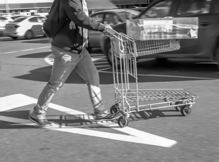 Blurred image of a man with a cart in a parking lotの写真素材