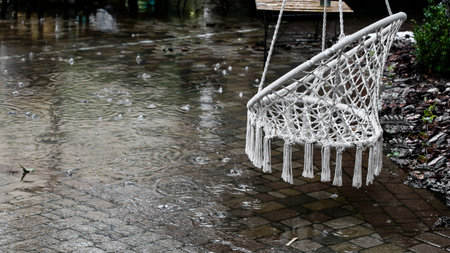 Hanging rope chair in a street cafe in the rainの写真素材
