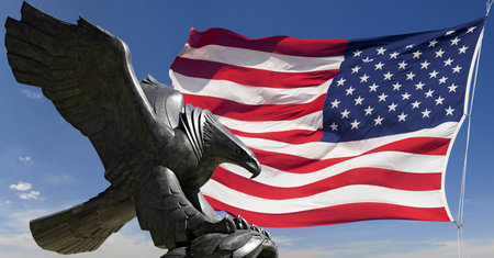 Eagle sculpture and American flag against the sky