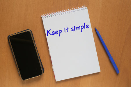 Open notebook with inscription: Keep it simple, mobile phone and marker on tableの写真素材