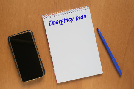Open notebook with description: Emergtncy plan, mobile phone and marker on tableの写真素材
