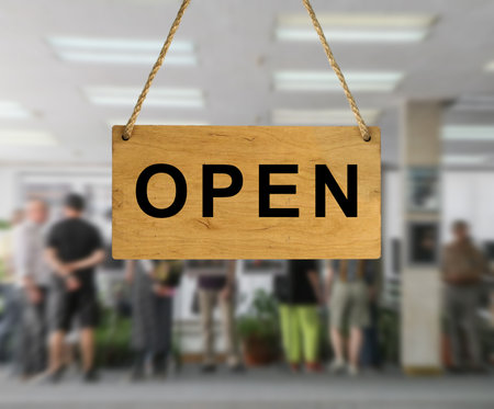 An Open sign against a blurred background of an interior with people