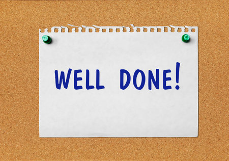 An advertisement âWell doneâ on a piece of paper attached to a notice boardの写真素材