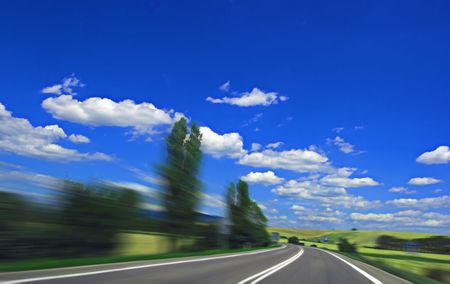 Asphalt highway with motion blur and blue cloudy sky