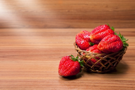 fresh strawberries in a small pottle on wooden tableの写真素材