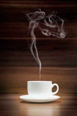 Cup of coffee with woman-shaped smoke on dark wood backgroundの写真素材