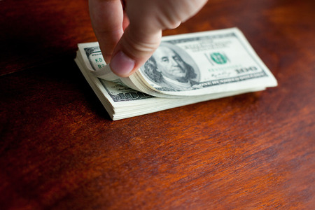 Dollar banknotes in hands on wooden desk