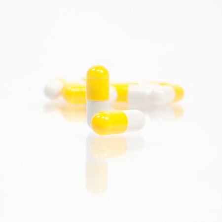 Yellow capsule pills on white backgroundの写真素材