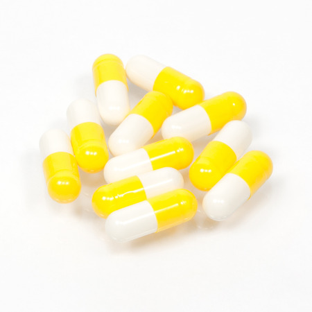 Yellow capsule pills on white backgroundの写真素材