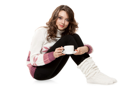 Young girl in a crocheted clothes with cup of coffeeの写真素材