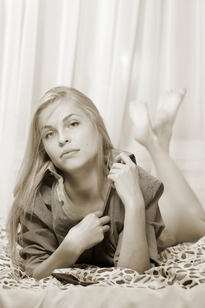 Woman lying at the bed. Sepia toned.の写真素材
