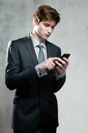 Young businessman using a mobile phone, on gray backgroundの写真素材