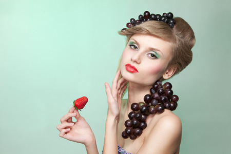 Young woman with strawberry and bunch of grapesの写真素材