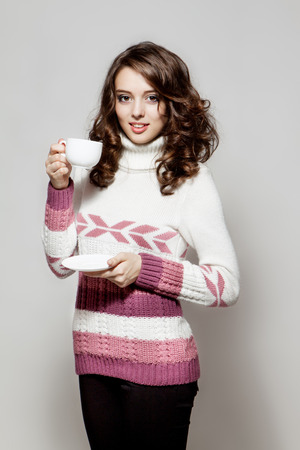 Young girl in a crocheted clothes with cup of coffeeの写真素材