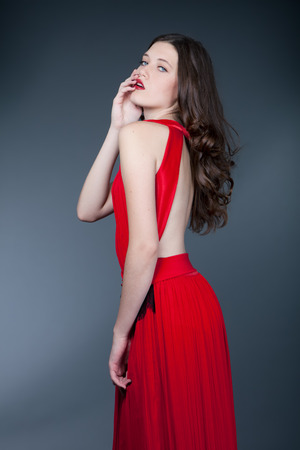 fashion model in red evening dress posing on gray background. Closeup.の写真素材